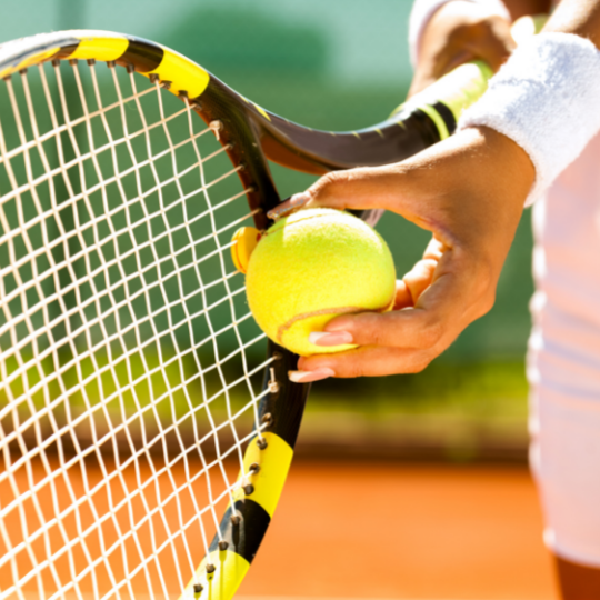 A hand hold a tennis ball onto a tennis racket